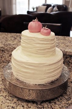 a white cake with two small pumpkins on top