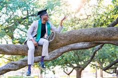 a man sitting on top of a tree branch wearing a graduation hat and holding his hand out