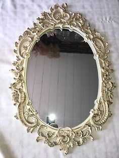 an ornate gold framed mirror sitting on top of a white tablecloth covered floor next to a window