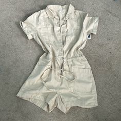 Tan Romper With Adjustable Waist String Buttons Down The Front And Pockets Beach Button-up Jumpsuits And Rompers With Buttons, Summer Button-up Medium Wash Jumpsuits And Rompers, Cotton Button-up Jumpsuits And Rompers With Button Closure, Summer Utility Button-up Jumpsuits And Rompers, Cotton Utility Button-up Jumpsuits And Rompers, Womens Navy Dress, Velour Jumpsuit, Navy Jumper, White Overalls