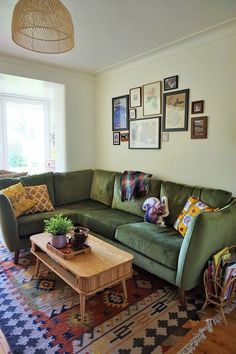 a living room with green couches and pictures on the wall above it's coffee table