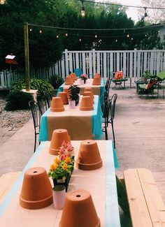 an outdoor dining area with blue table cloths and orange plastic hats on the tables