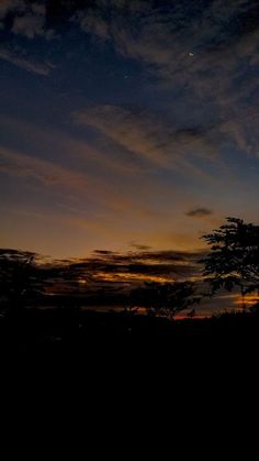 the sun is setting behind some trees and clouds in the sky with no one on it