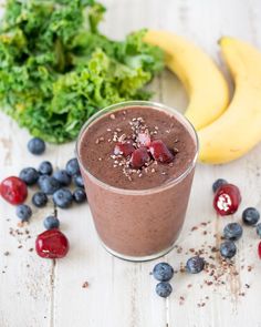 a smoothie with strawberries, blueberries and bananas on a white wooden table