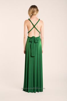 the back of a woman wearing a green dress with a cross - back and tie at the waist