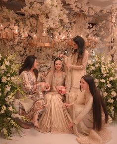 three women sitting next to each other in front of flowers and chandelier hanging from the ceiling