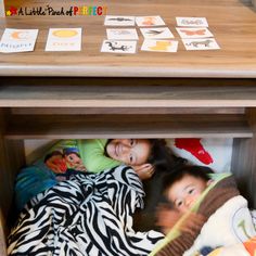 two children laying on the floor under a table