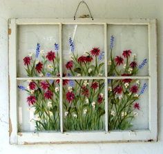 an old window with flowers painted on the glass and hanging from it's side