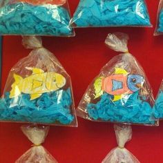 there are many bags of candy shaped like fish on the red wall, and one bag is filled with blue frosting