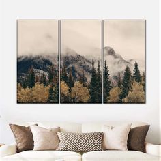 three canvases on the wall above a couch in a living room with mountains and trees