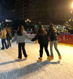 several people are skating on an ice rink at night