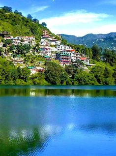 a lake surrounded by lush green hills and houses