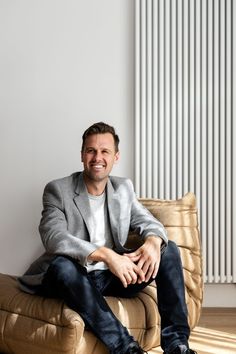 a man sitting on top of a brown couch next to a radiator in a room