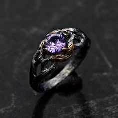 a ring with an amethorate stone in the center on a black surface