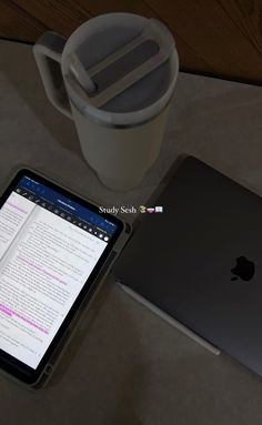 an open laptop computer sitting on top of a table next to a cup and coffee mug