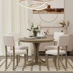 a dining room table with four chairs and a vase on the table next to it