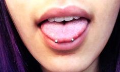 a woman with purple hair and piercings on her tongue