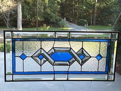 a stained glass window hanging from the side of a building with trees in the background