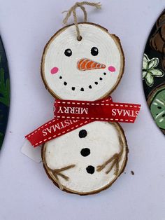 two snowmen made out of wood slices with red ribbon around their necks and faces