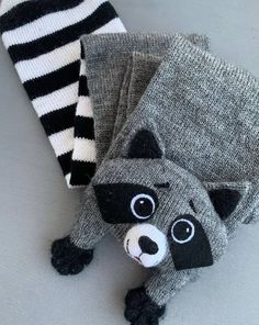 two stuffed raccoons are laying on the floor next to each other, one is wearing a striped sock