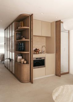 a kitchen with an oven, microwave and cabinets in it's corner area next to a living room