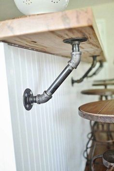 an industrial pipe is attached to the wall above a table with stools and tables in the background