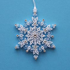 a snowflake ornament on a blue background with white string and beads