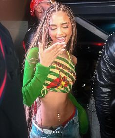 a woman with dreadlocks standing in front of a car