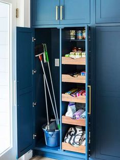 a blue cabinet with two bins filled with cleaning supplies and a mop in it