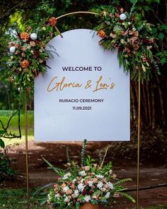 a welcome sign with flowers and greenery on it