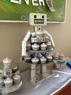 a robot made out of cupcakes sitting on top of a silver table cloth