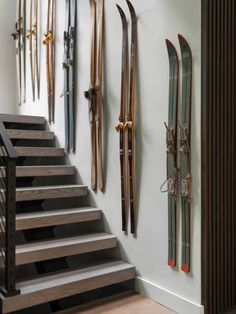 there are many skis hanging on the wall next to the stair case in this room