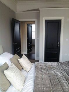 a bed room with a neatly made bed and two black doors on the side of it