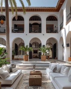 a large courtyard with couches, tables and potted plants