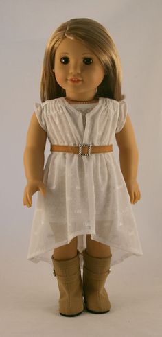 a doll with brown hair wearing a white dress and tan boots, standing in front of a white background