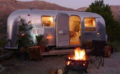 a camper trailer is lit up by the fire pit