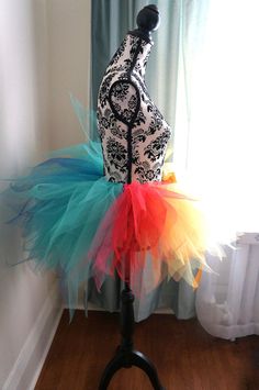 a mannequin with colorful tulle and lace on it's body in front of a window