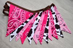 pink and black cow print bandana with brown leather straps on a white tablecloth