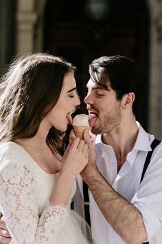 a man and woman sharing a pastry together in front of an old building with the door open