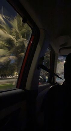 a view from the back seat of a car at night with palm trees in the background