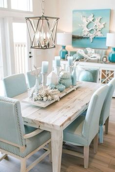 a dining room table with blue chairs and a white chandelier hanging from the ceiling