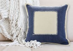 a blue and white pillow sitting on top of a couch next to a throw blanket