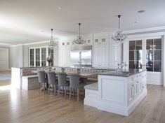 a large kitchen with white cabinets and an island in the middle is surrounded by gray chairs