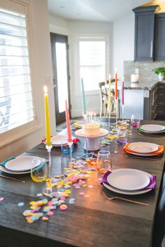 a table with plates and candles on it in the middle of a room filled with confetti