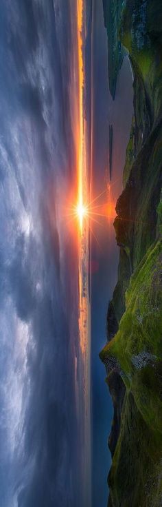 the sun is shining brightly through the clouds above an ocean cliff and cliffs with green grass on either side