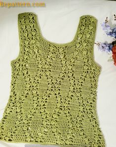 a green crocheted tank top next to flowers