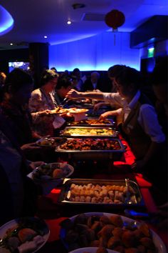 many people are serving themselves food at a buffet