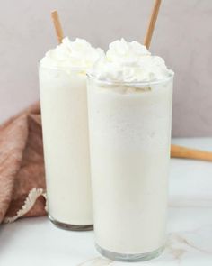 two glasses filled with whipped cream on top of a table