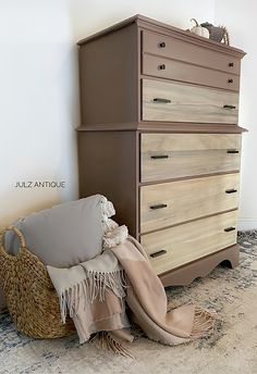 a brown dresser sitting on top of a carpeted floor next to a basket filled with pillows