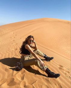 a woman sitting on top of a sandy dune